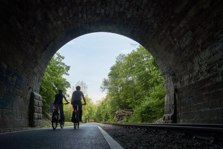 Radfahrer fahren durch einen Tunnel auf dem Kanonenbahnradweg